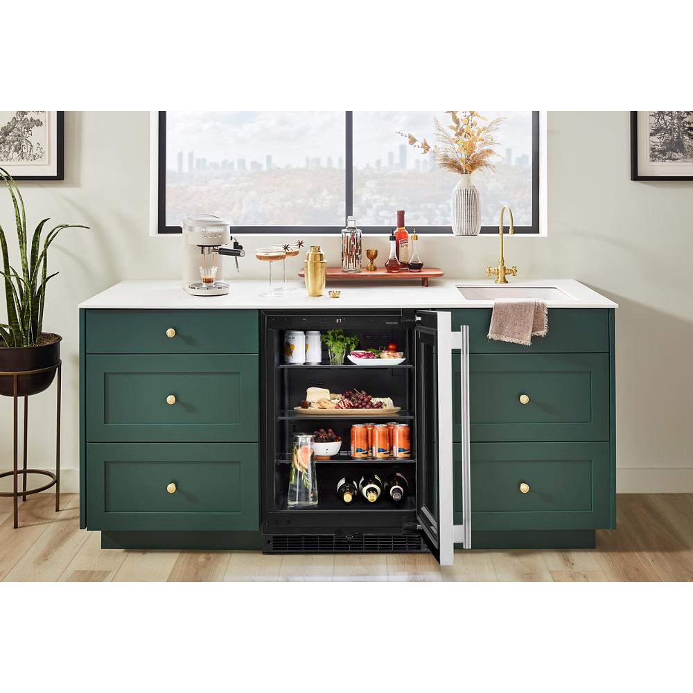 24-inch undercounter refrigerator with glass door open, stocked with beverages and snacks in modern kitchen setting