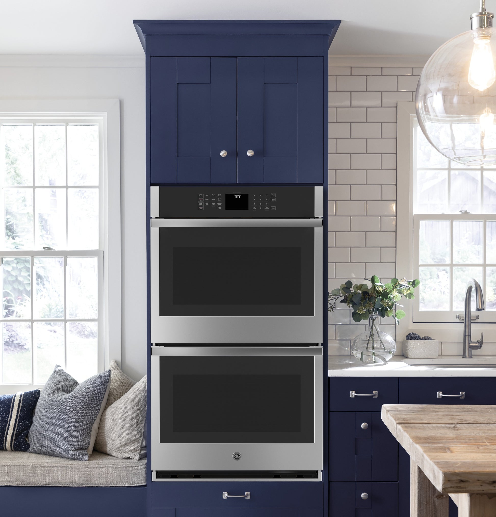 Built-in stainless steel double wall oven integrated into navy blue cabinetry in modern kitchen setting