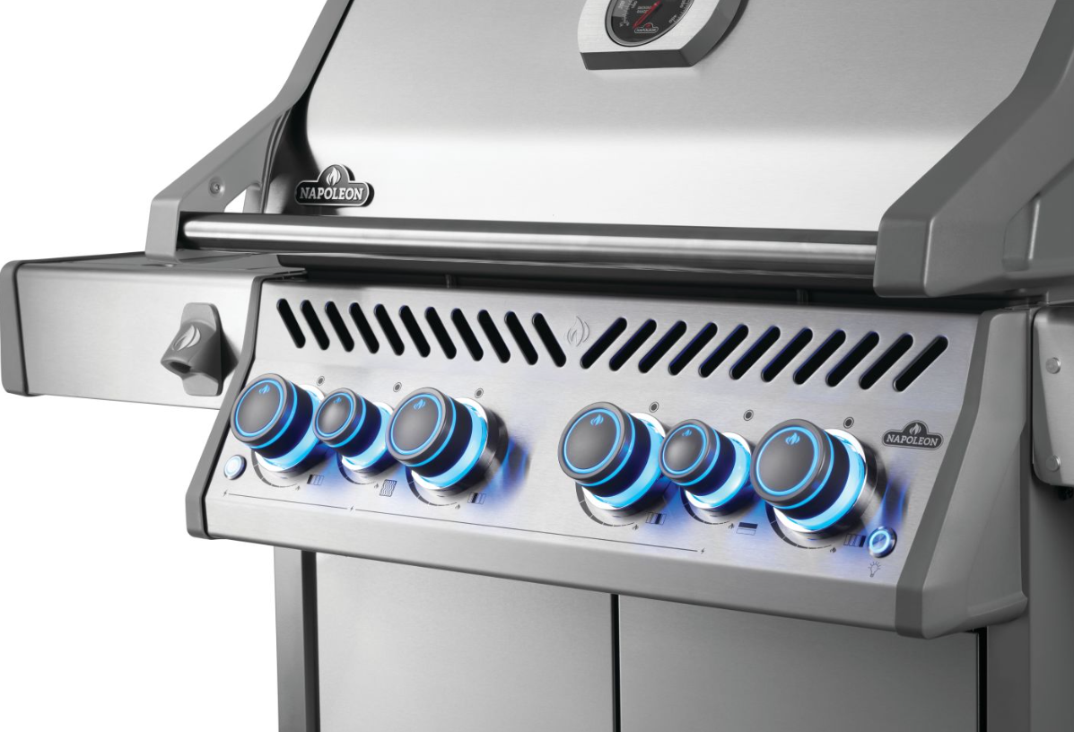 Napoleon stainless steel natural gas grill with six blue LED illuminated control knobs, built-in thermometer, and vented front panel for outdoor cooking and grilling.