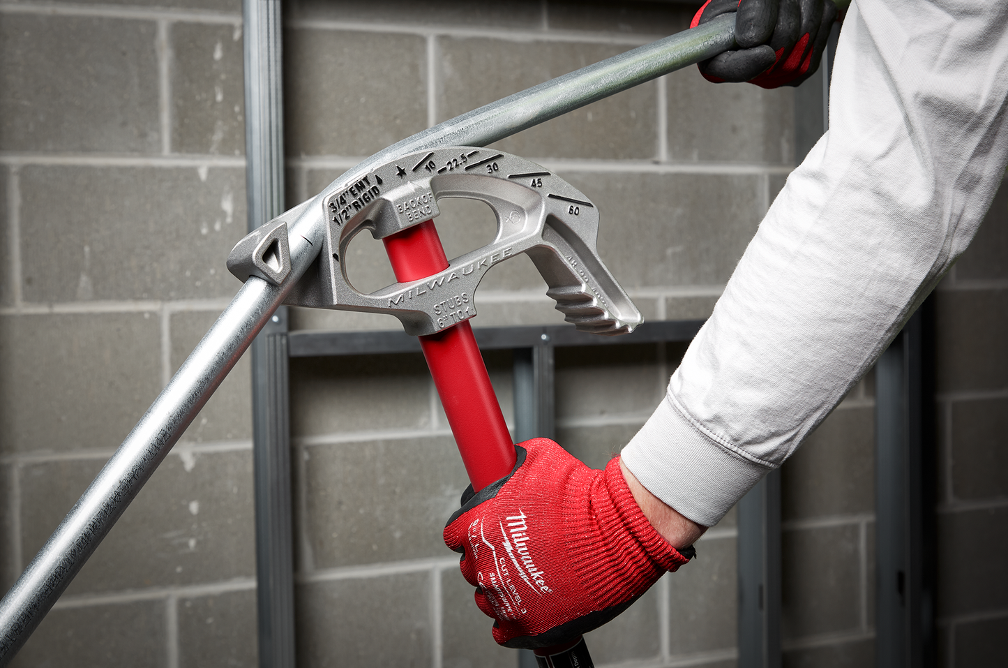 Milwaukee aluminum bender with red handle bending 3/4-inch EMT conduit pipe in home improvement setting