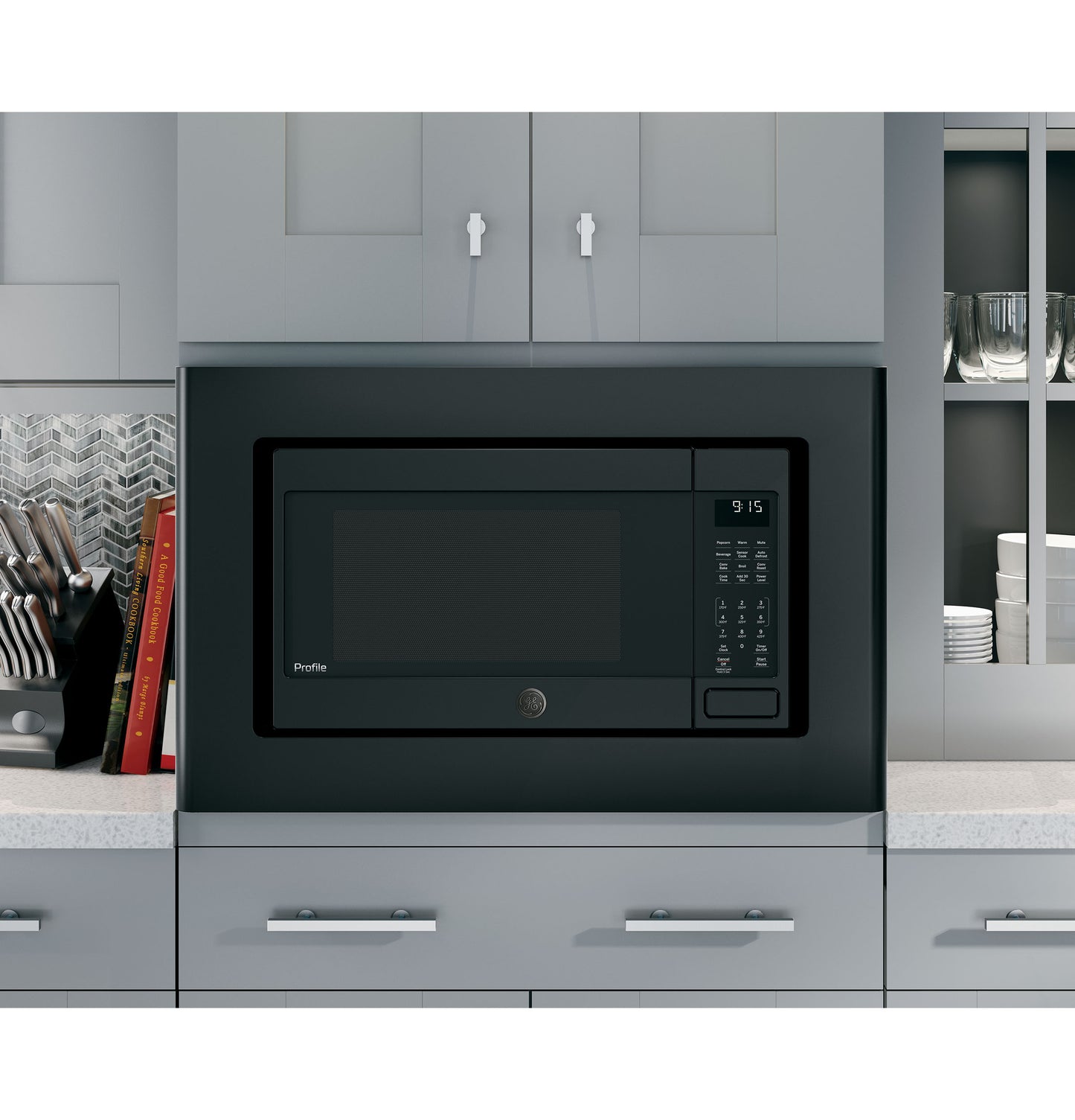Black trim kit framing built-in microwave in modern gray kitchen with silver handles and open shelving nearby