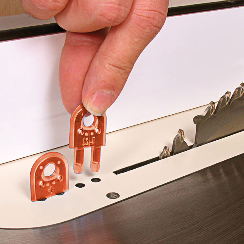 Hand inserting copper-colored safety insert into table saw next to sharp blade in tools and saw accessories category