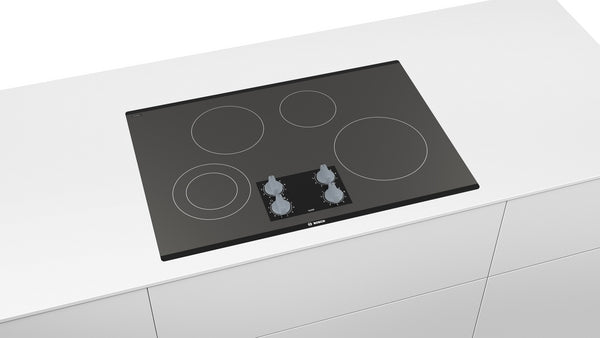 Black seamless electric cooktop with four burners and front control knobs in Bosch kitchen and appliances collection