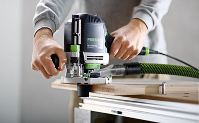 Person using a Festool woodworking router on a wooden surface, demonstrating precision and control in tools collection