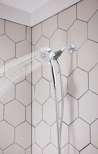 Chrome handheld showerhead with six spray settings mounted on tiled shower wall for home improvement use