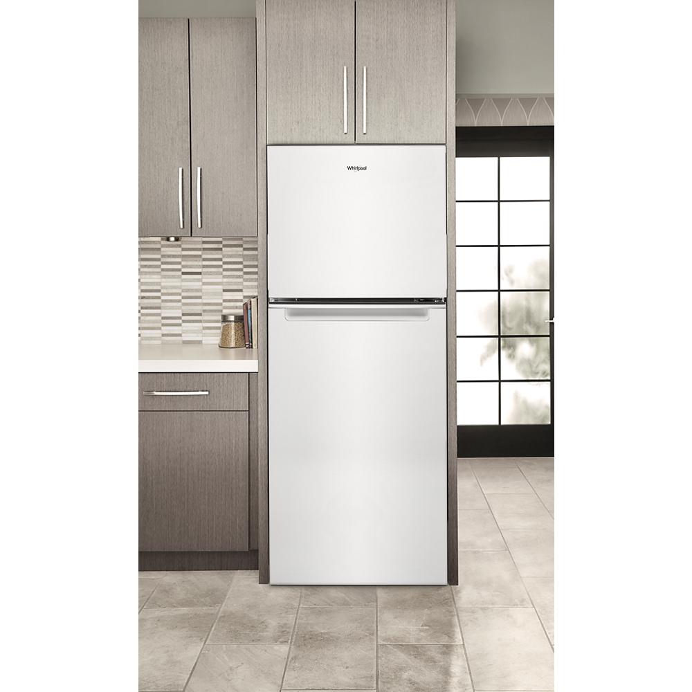 White Whirlpool top-freezer refrigerator integrated into modern kitchen with tiled backsplash and wood cabinetry