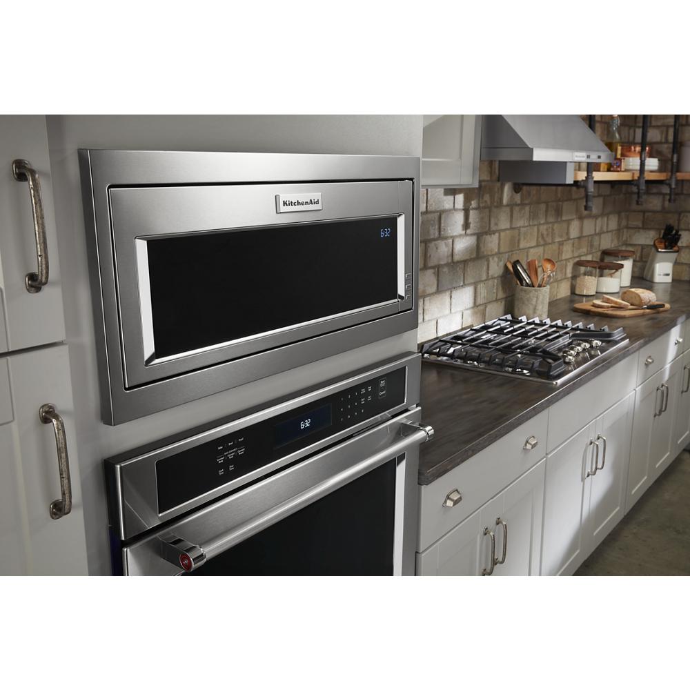 Stainless steel built-in microwave and wall oven installed in modern kitchen with gray cabinetry and tile backsplash
