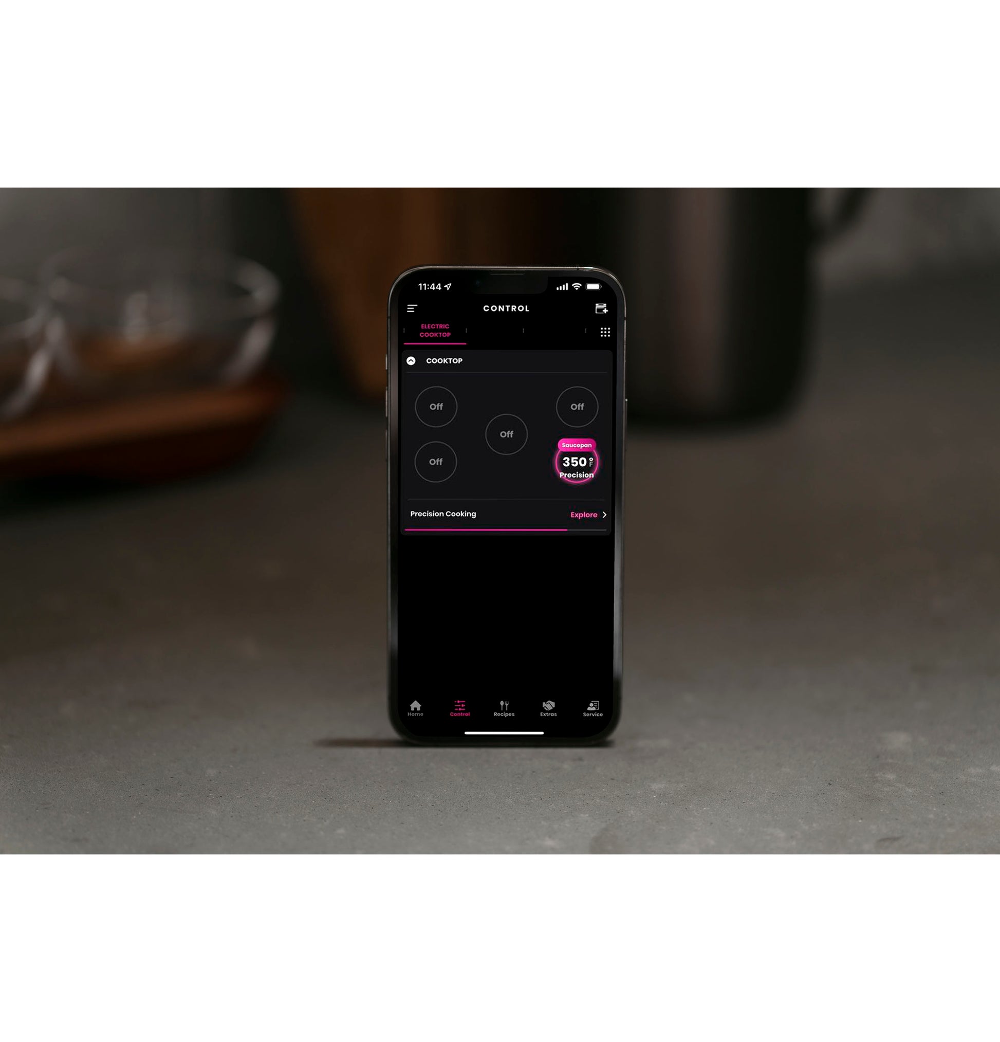 Smartphone displaying remote control interface for GE Profile™ 30" touch control electric cooktop on kitchen countertop