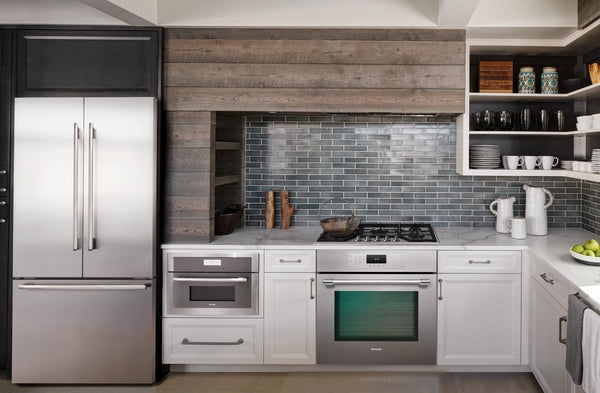 Modern kitchen featuring stainless steel built-in microwave and oven with white cabinetry and a gray tile backsplash