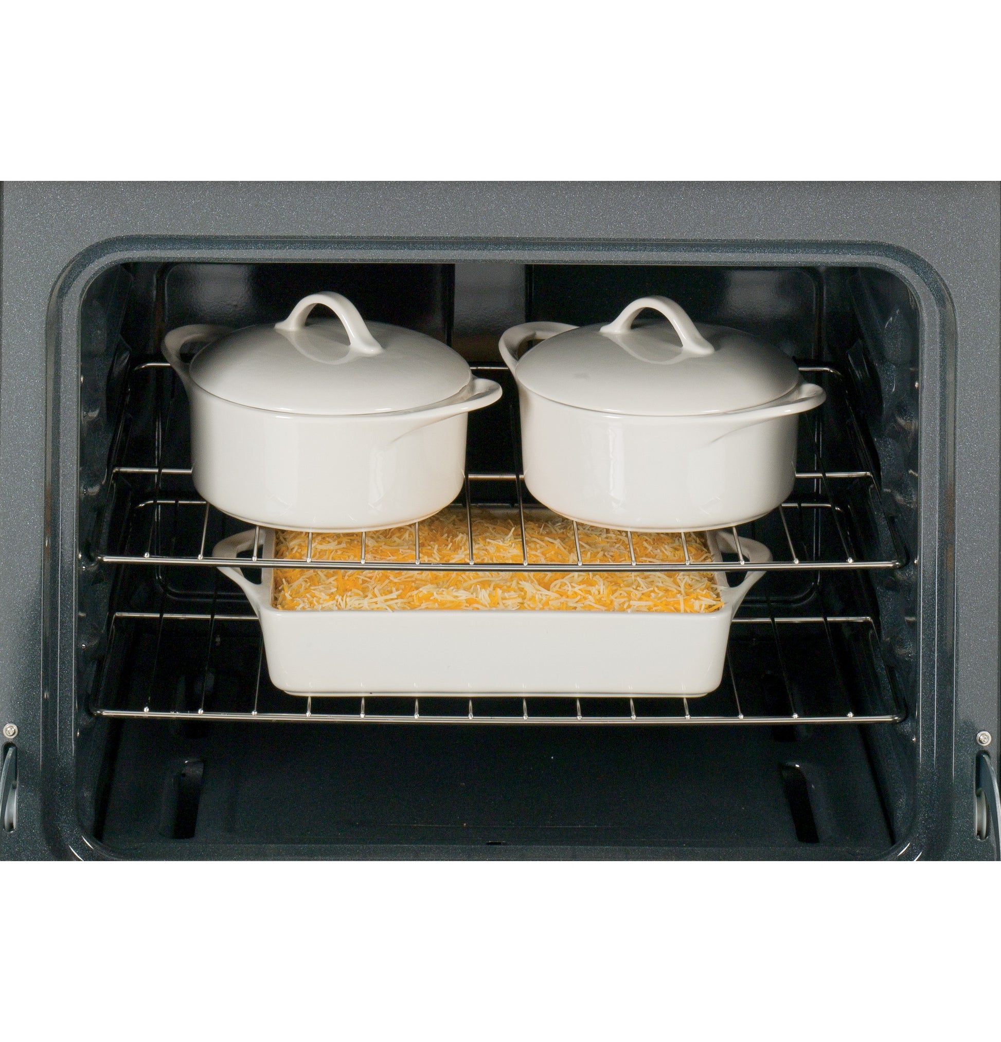 Interior view of open oven with two white covered pots on top rack and casserole dish with baked dish below in kitchen appliances collection