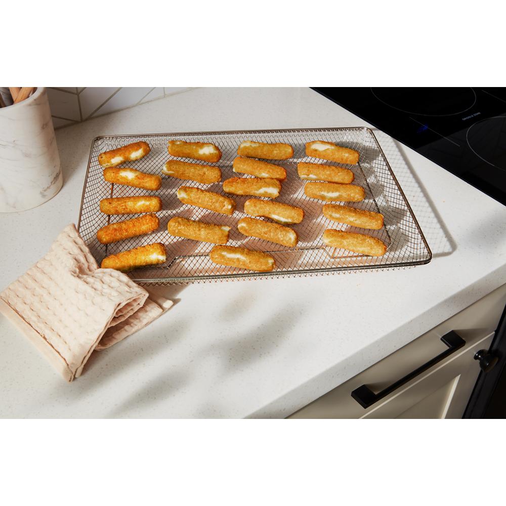 golden brown breaded mozzarella sticks cooling on wire rack on white kitchen countertop near stovetop