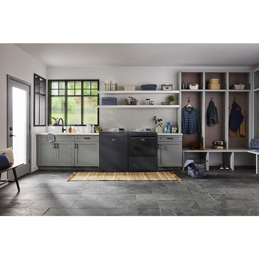 Modern laundry room featuring dark gray top load gas dryer and matching washer with open shelving and storage cubbies from Dryers collection