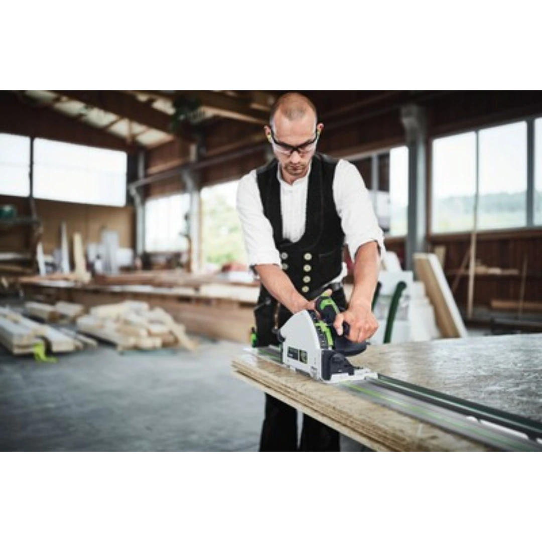Man using Festool track saw with guide rail for precise woodworking cuts in a spacious woodshop setting