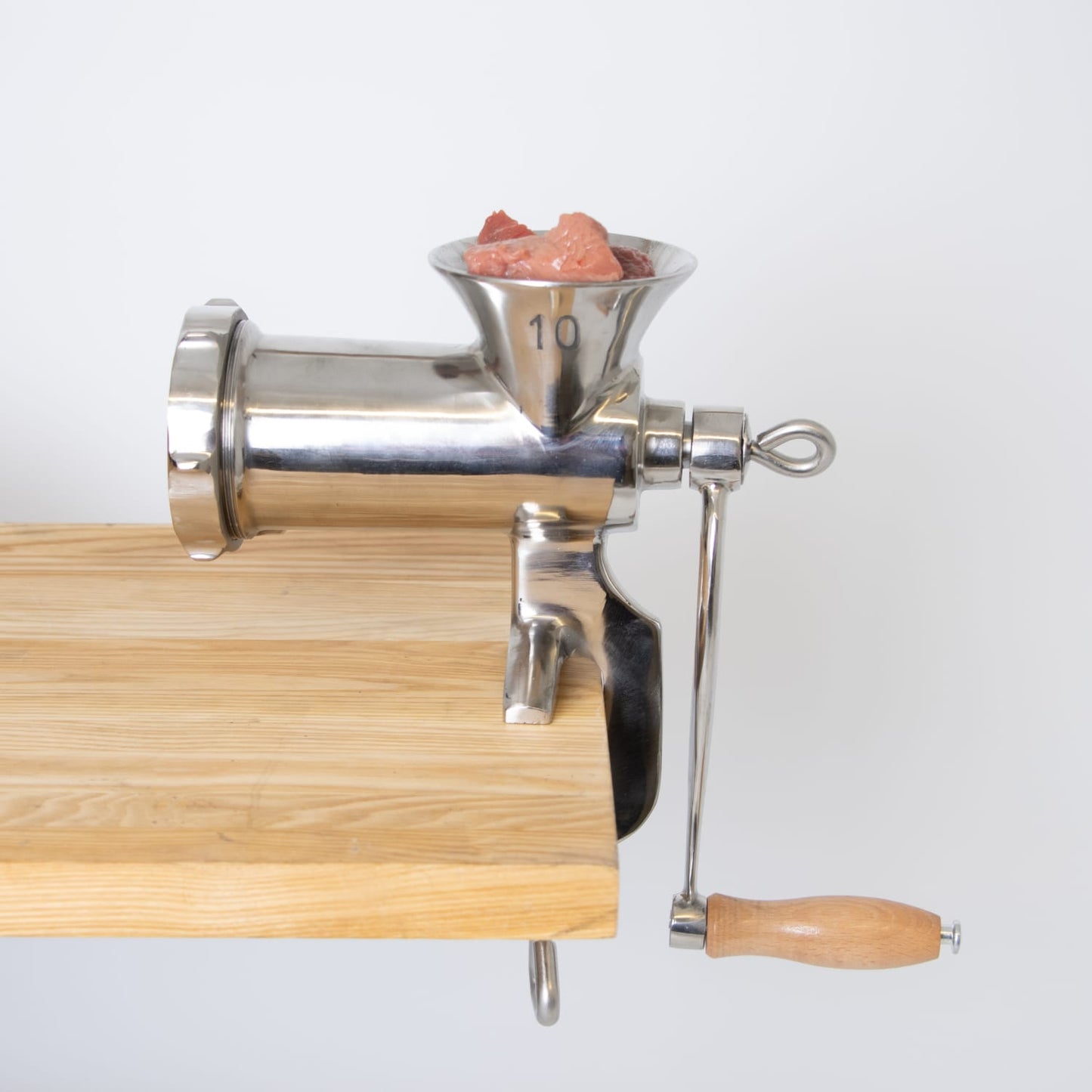 Manual clamp-on meat grinder with wooden handle attached to wood surface in kitchen gadgets under $100 collections