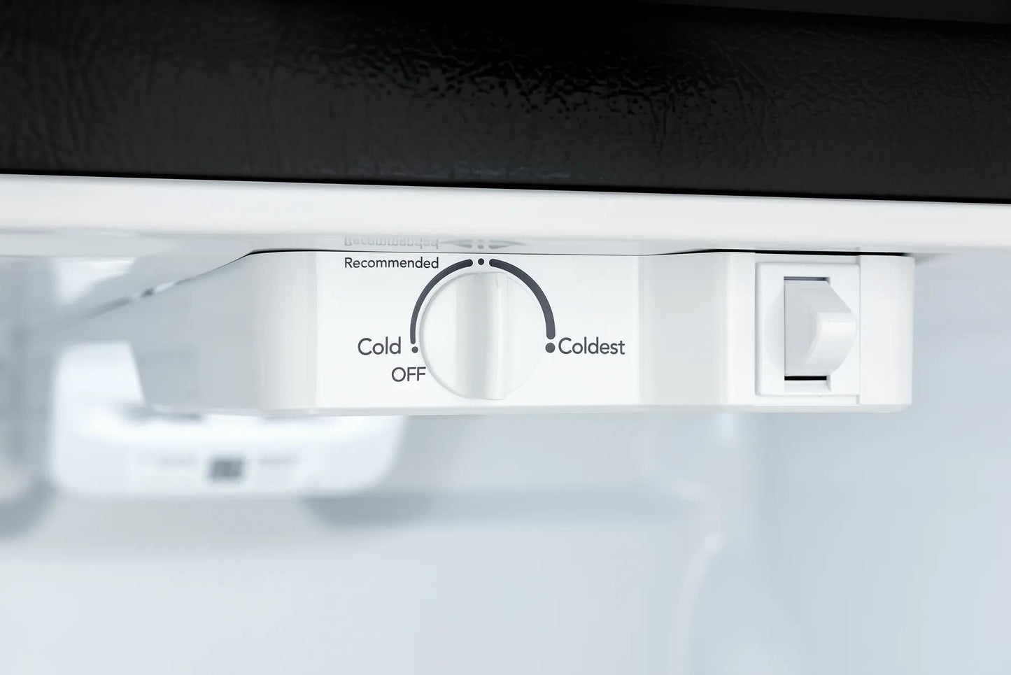 Close-up of white temperature control dial inside top freezer of refrigerator in appliances collection