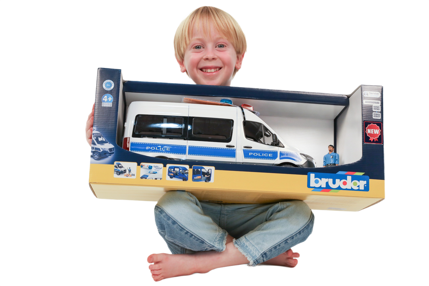 Smiling child holding boxed Bruder MB Sprinter police emergency vehicle toy with blue and white design