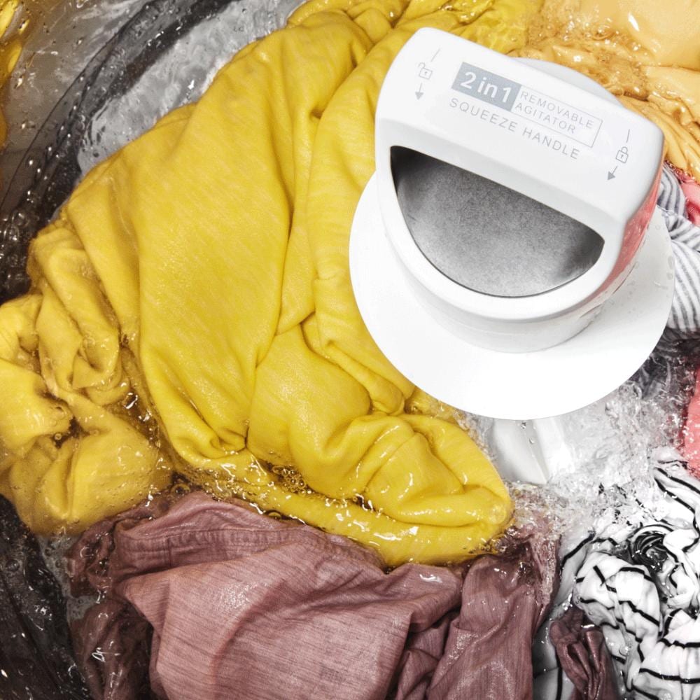 Close-up of yellow and pink laundry tumbling inside a top load washer with removable 2 in 1 agitator in motion