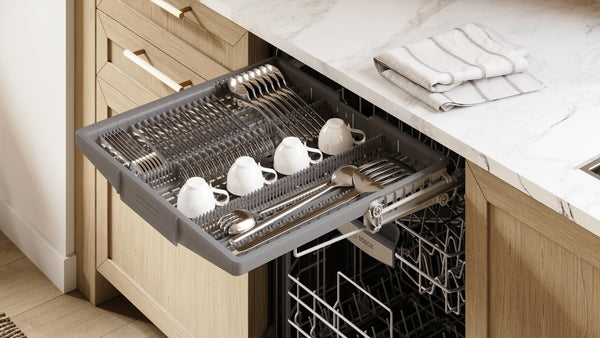 Open dishwasher drawer with clean white cups and silverware in light wood kitchen featuring marble countertop