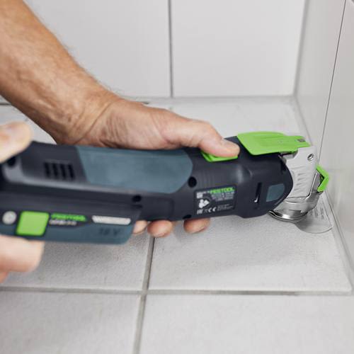 Festool oscillating tool with round blade cutting grout from tiled floor corner for home improvement projects