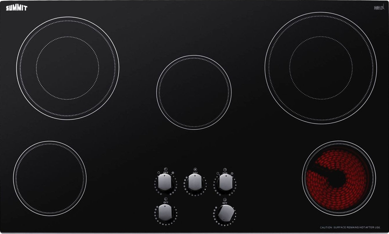 Black smooth-top radiant cooktop with five burners and five control knobs in modern kitchen appliances collection