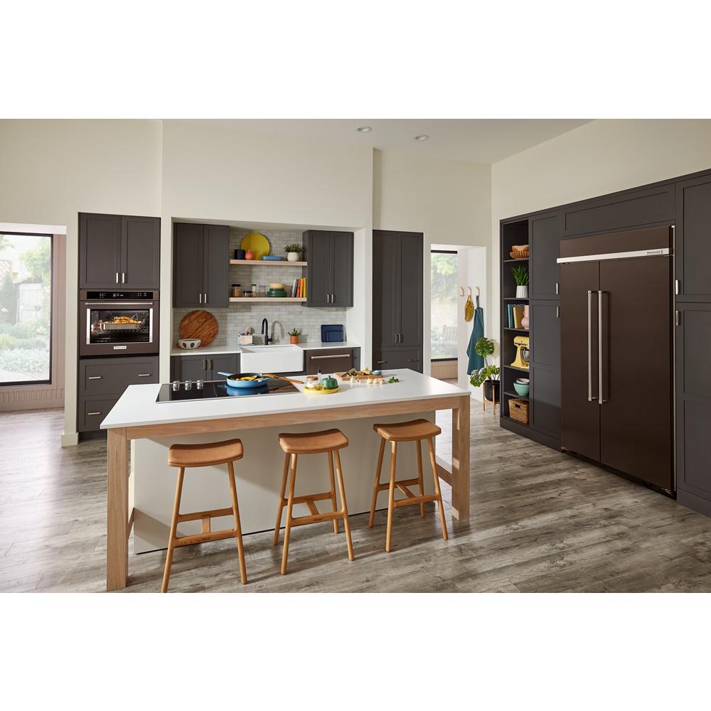 Contemporary kitchen with dark built-in ovens, large island with wood stools, and modern farmhouse sink in bright space