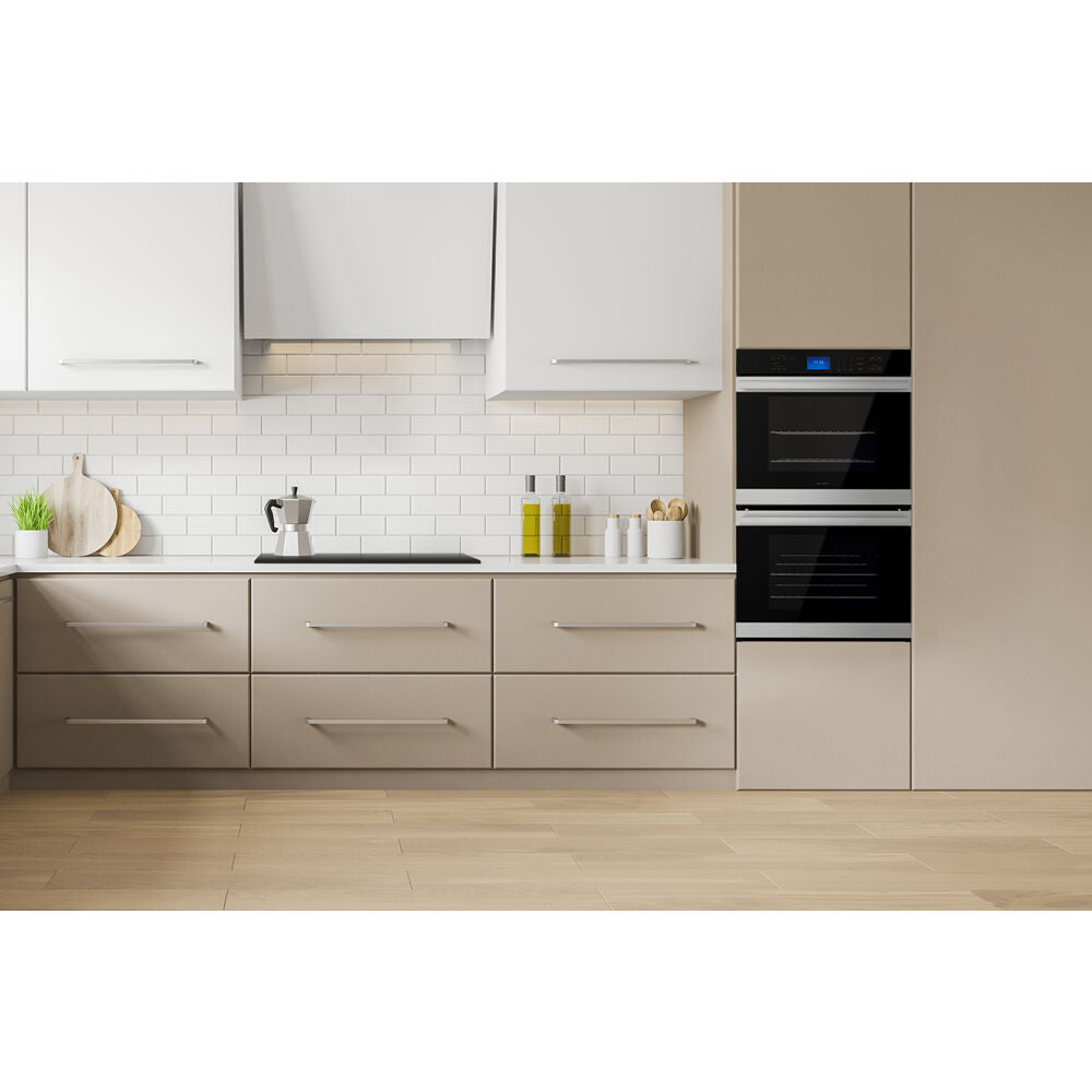 Modern kitchen with built-in black glass double wall oven surrounded by beige cabinetry and white subway tile backsplash
