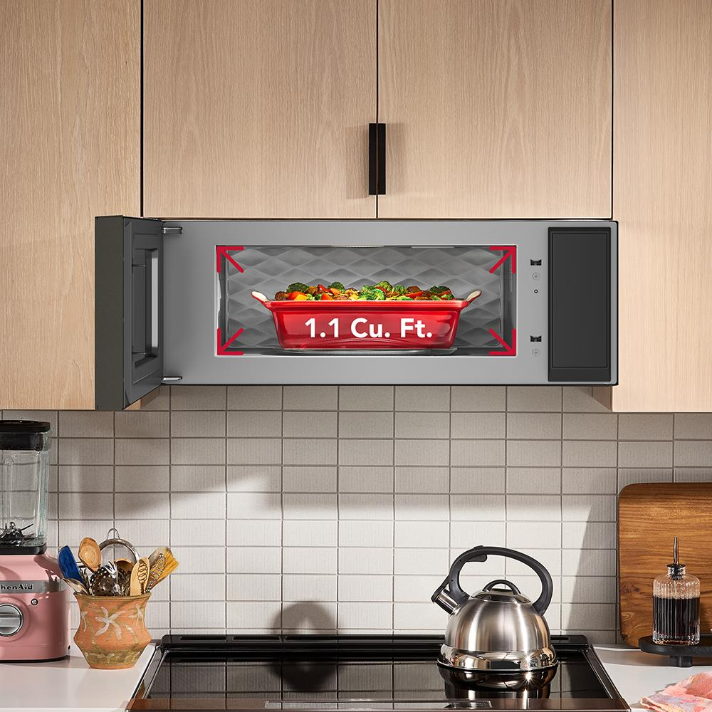 Open low profile microwave with 1.1 cu. ft. capacity installed above black electric cooktop in modern KitchenAid kitchen setup