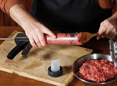 Hand filling clear jerky gun with ground meat on wooden board for kitchen appliance use under $50 collections