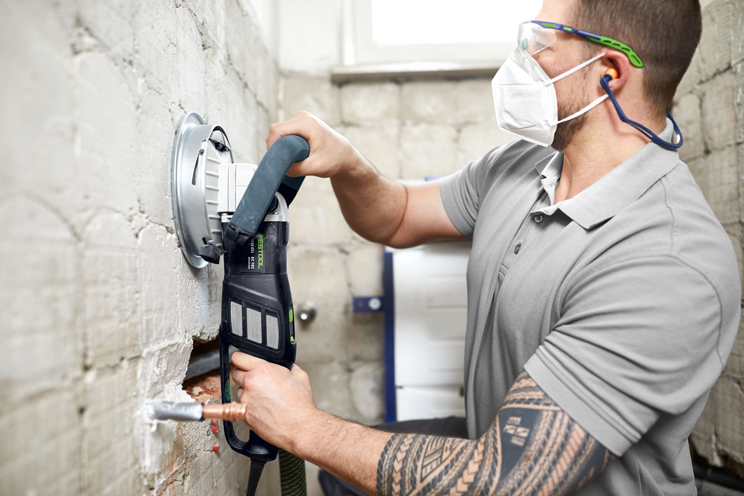 Worker using Festool diamond grinder with dust extraction smoothing interior wall during home improvement project