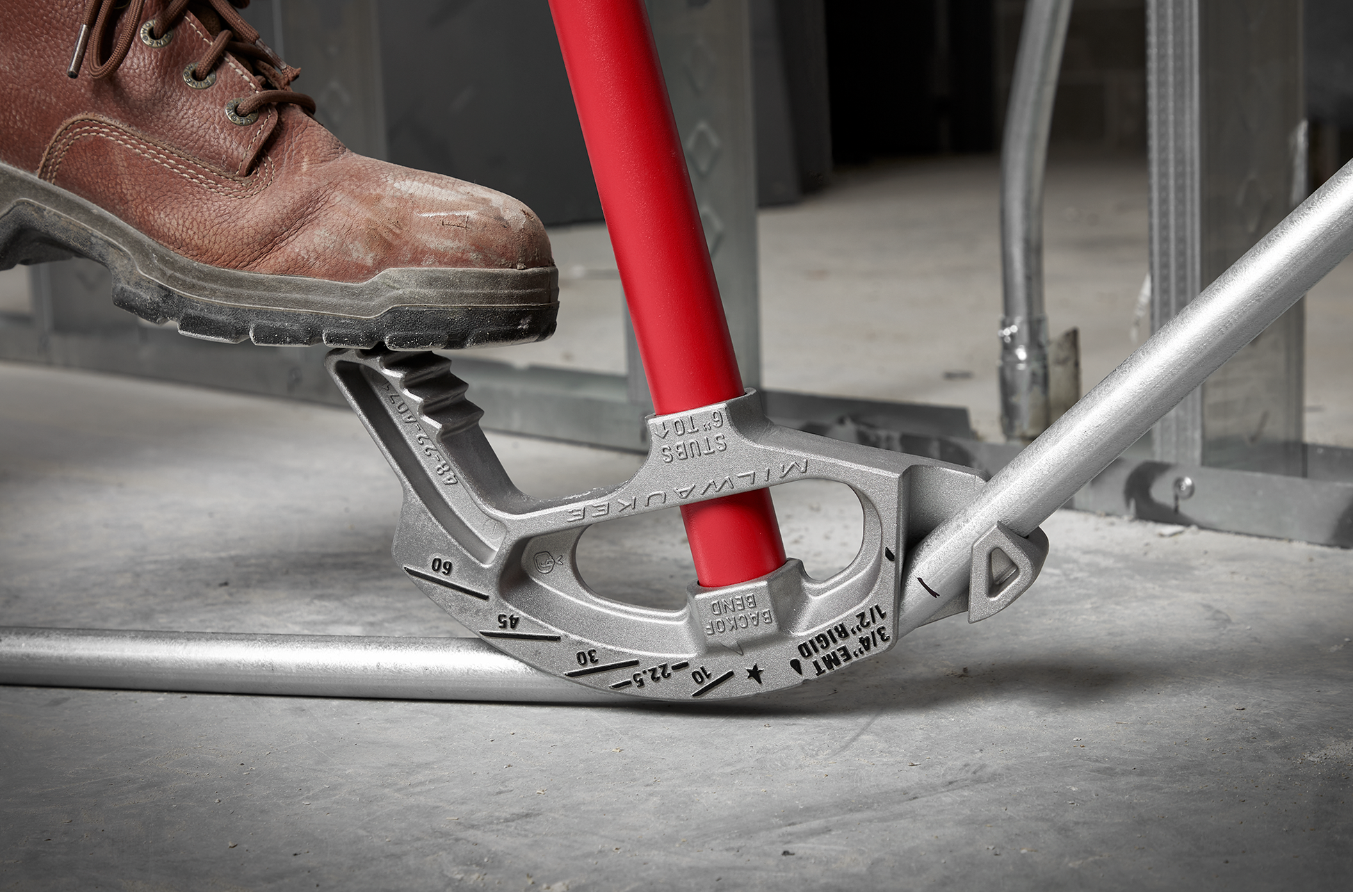 Milwaukee 3/4 EMT aluminum conduit bender with red handle bending metal pipe on concrete floor in construction setting