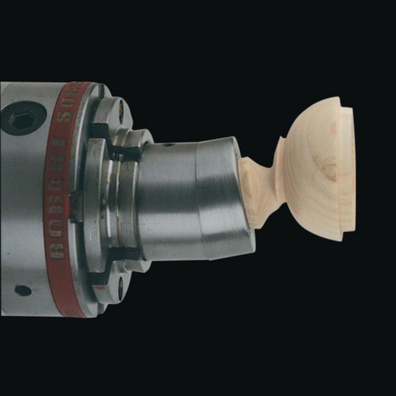 Metal lathe chuck holding a wooden spindle blank for precision woodworking and tool projects