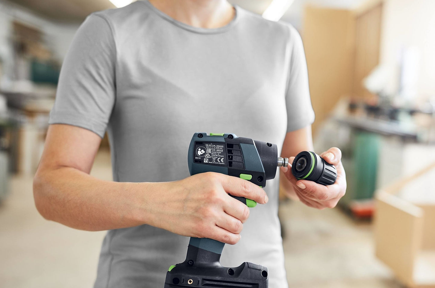 Person attaching drill bit to compact cordless power tool, ideal for woodworking and home improvement tasks