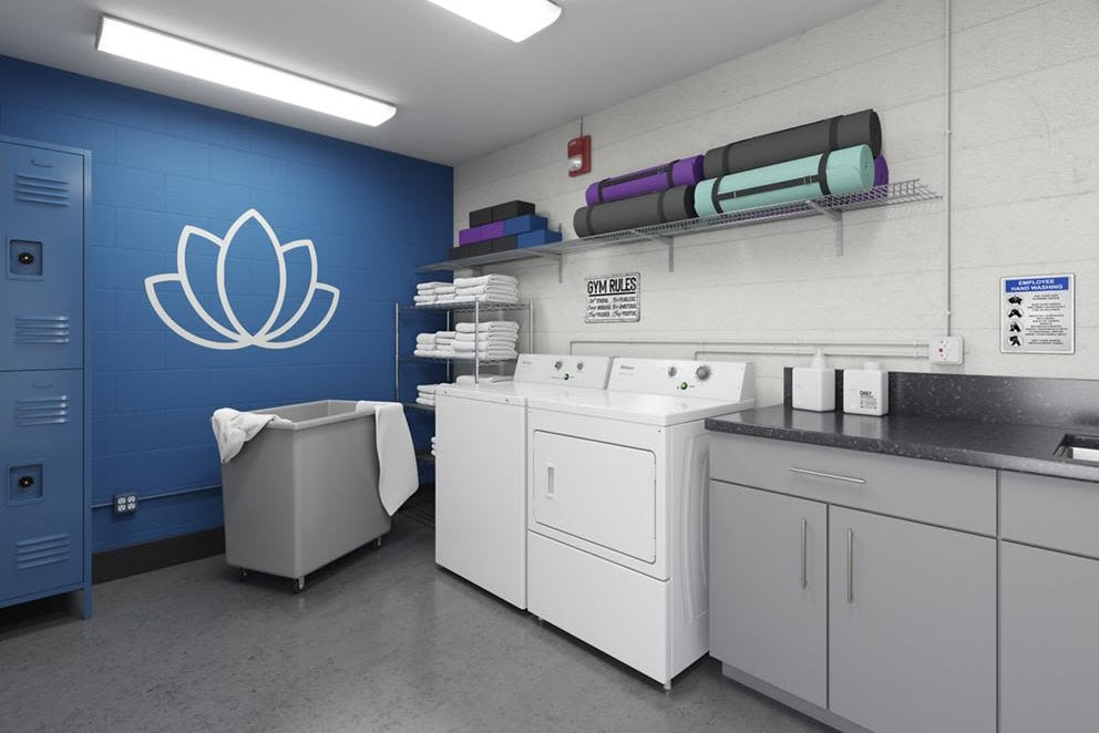 White commercial gas dryer paired with matching washer in organized laundry room with folded towels and lockers