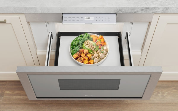 Stainless steel microwave drawer with pull-out tray showcasing heated healthy meal in kitchen appliances collection
