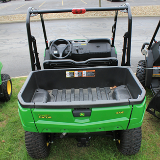 Rear view of green mid-size utility vehicle with large cargo bed and 4x4 drivetrain for outdoor use