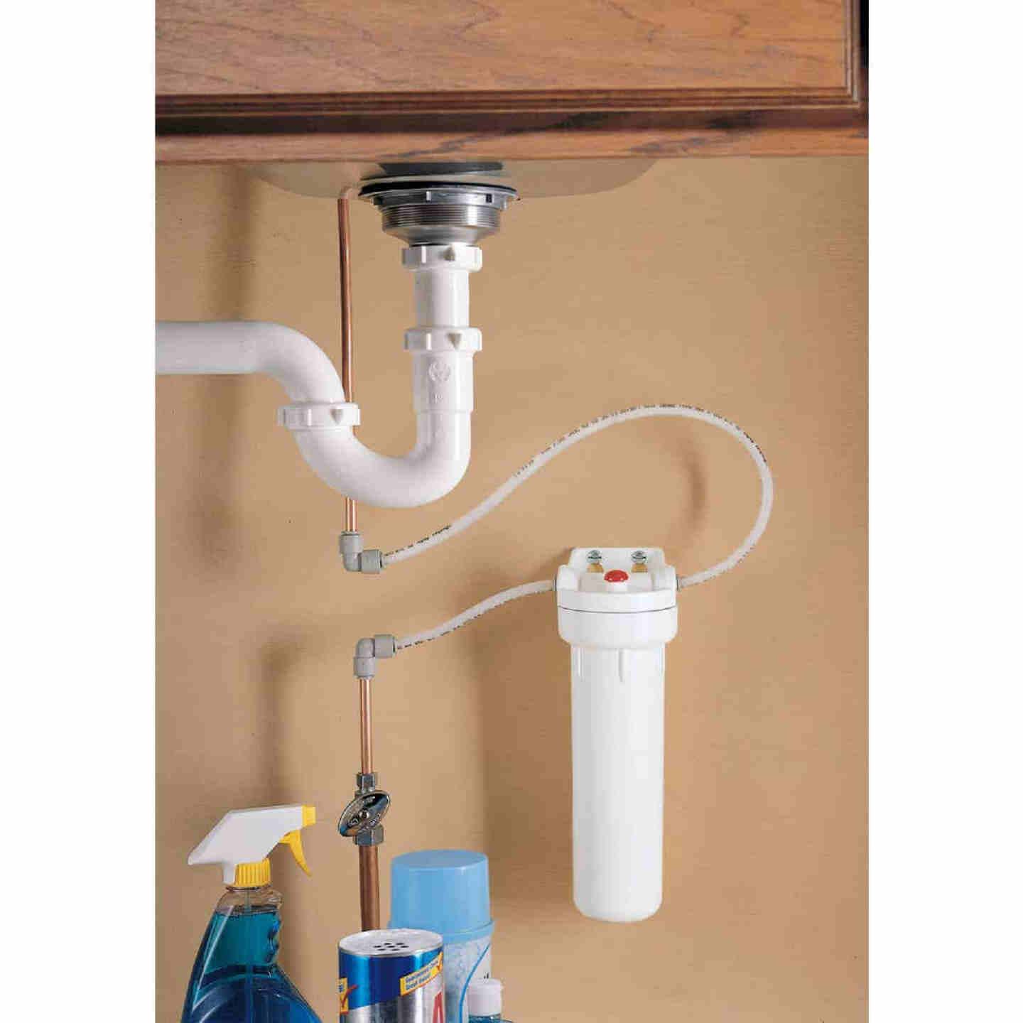 White cylindrical water filtration system installed under a sink with plumbing and cleaning supplies nearby