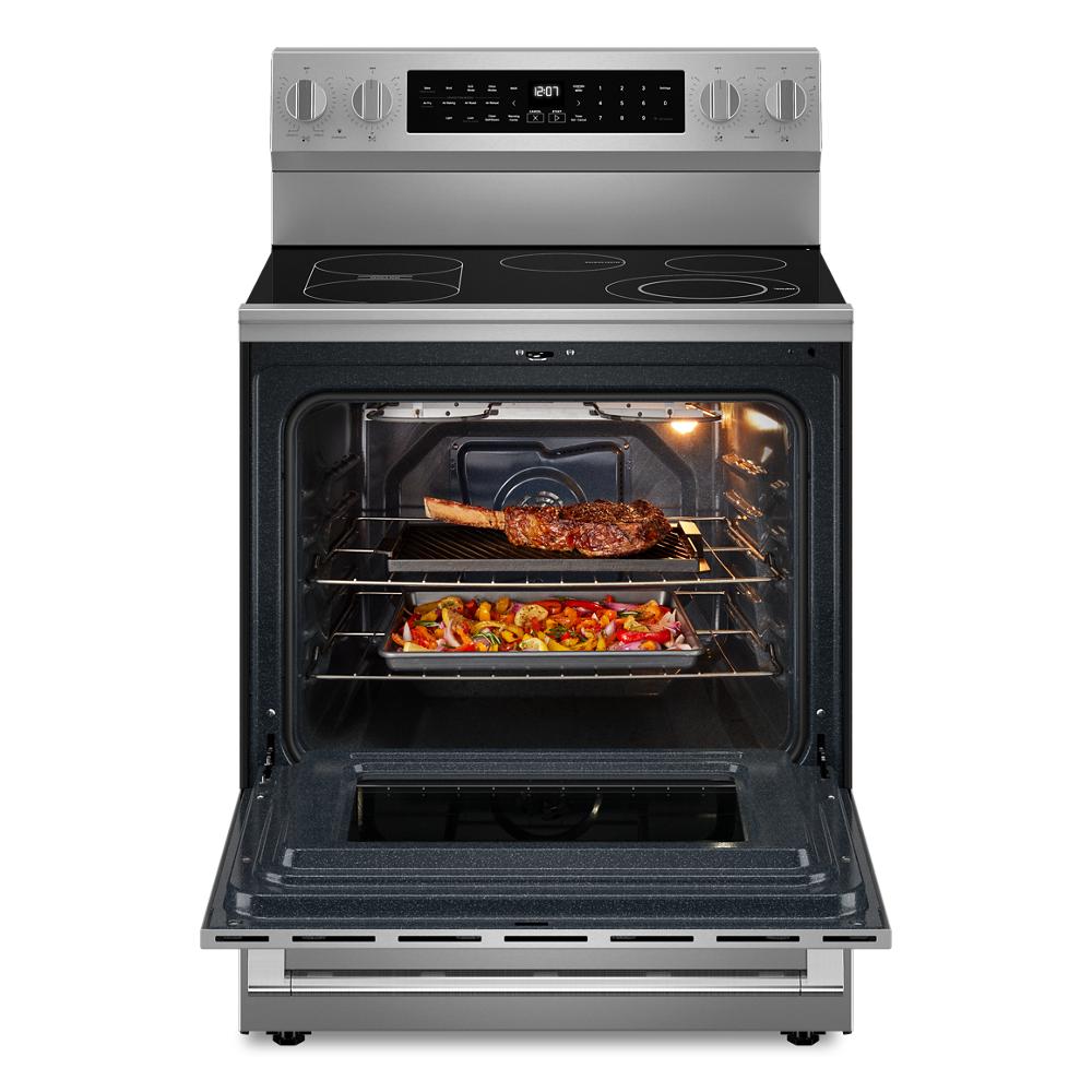 Front view of stainless steel electric range with open oven containing cooked steak and roasted vegetables in ranges collection