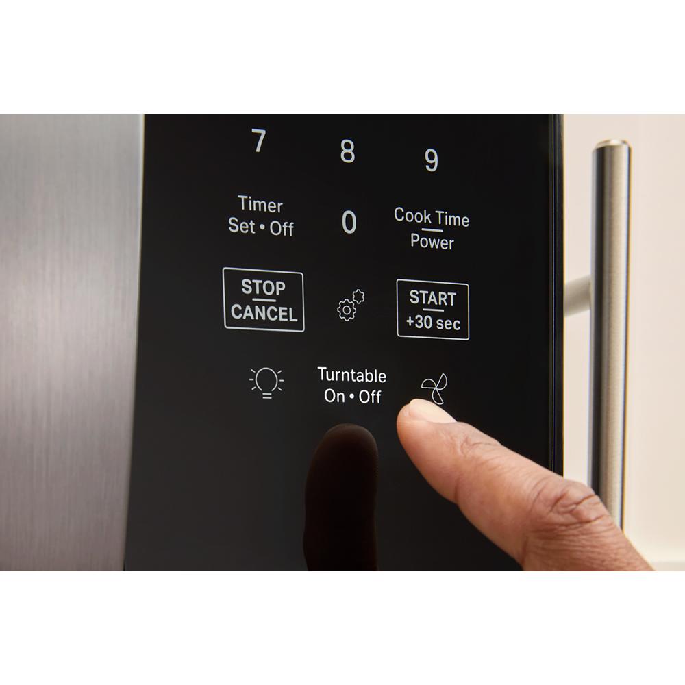Finger pressing fan button on digital control panel of stainless steel over the range microwave from kitchen appliances collection