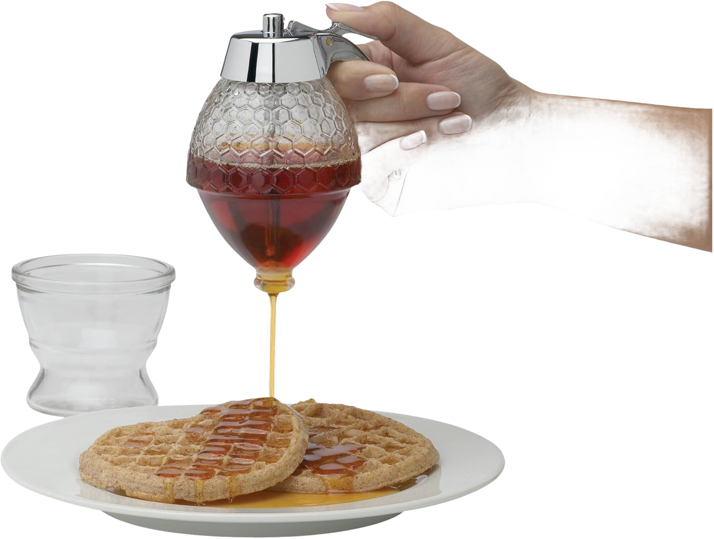 Glass honeycomb-patterned syrup dispenser with chrome lid pouring syrup on waffles in kitchenware and food storage collection