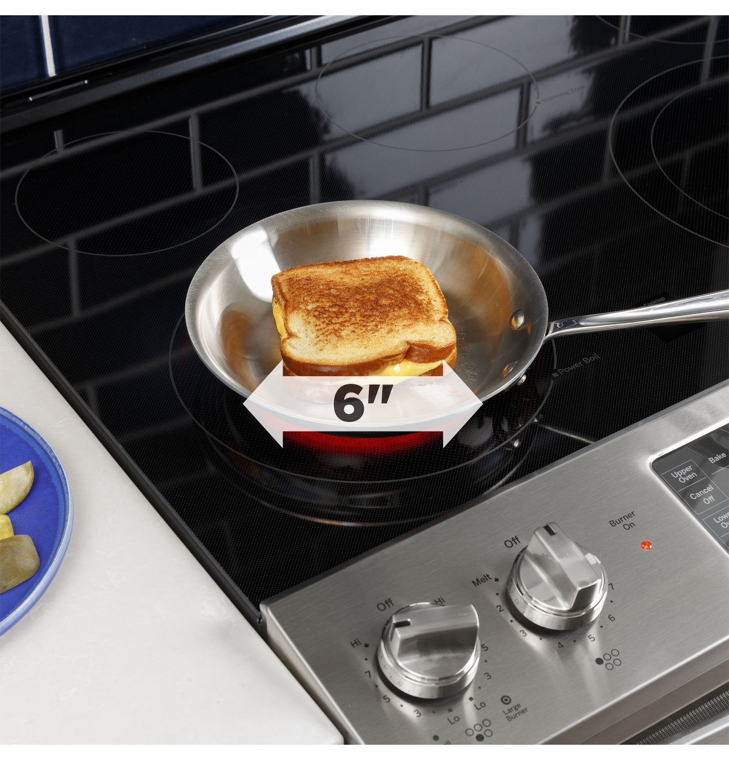 6-inch stainless steel skillet cooking grilled cheese sandwich on black electric glass cooktop burner with control knobs