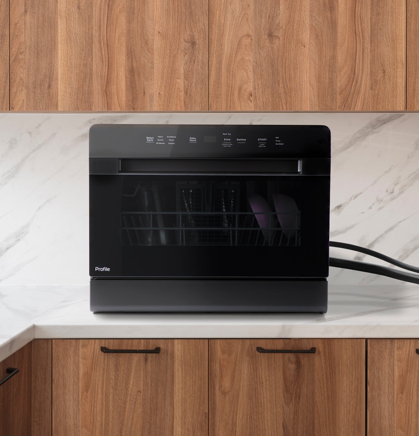 Black compact dishwasher with digital touch controls on marble countertop in modern kitchen setting