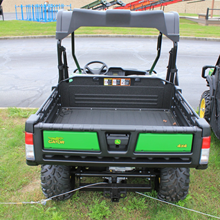 Rear view of a green utility vehicle with cargo bed and protective roof for outdoor work and hauling tasks