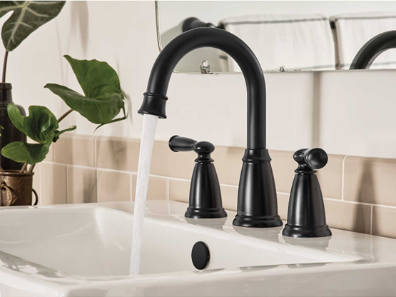 Matte black two-handle high arc widespread faucet installed on a white bathroom sink for home improvement