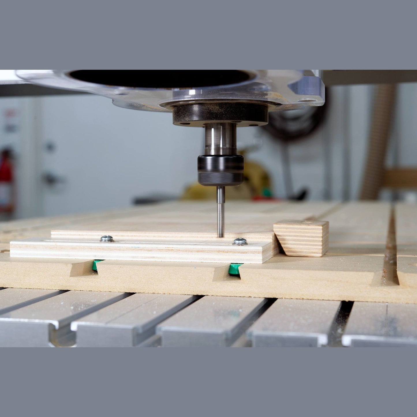 Router bit cutting into wood held by adjustable dovetail hardware clamps in a woodworking workshop setting