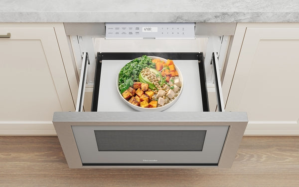 Built-in stainless steel microwave drawer open with bowl of vegetables in modern kitchen setting