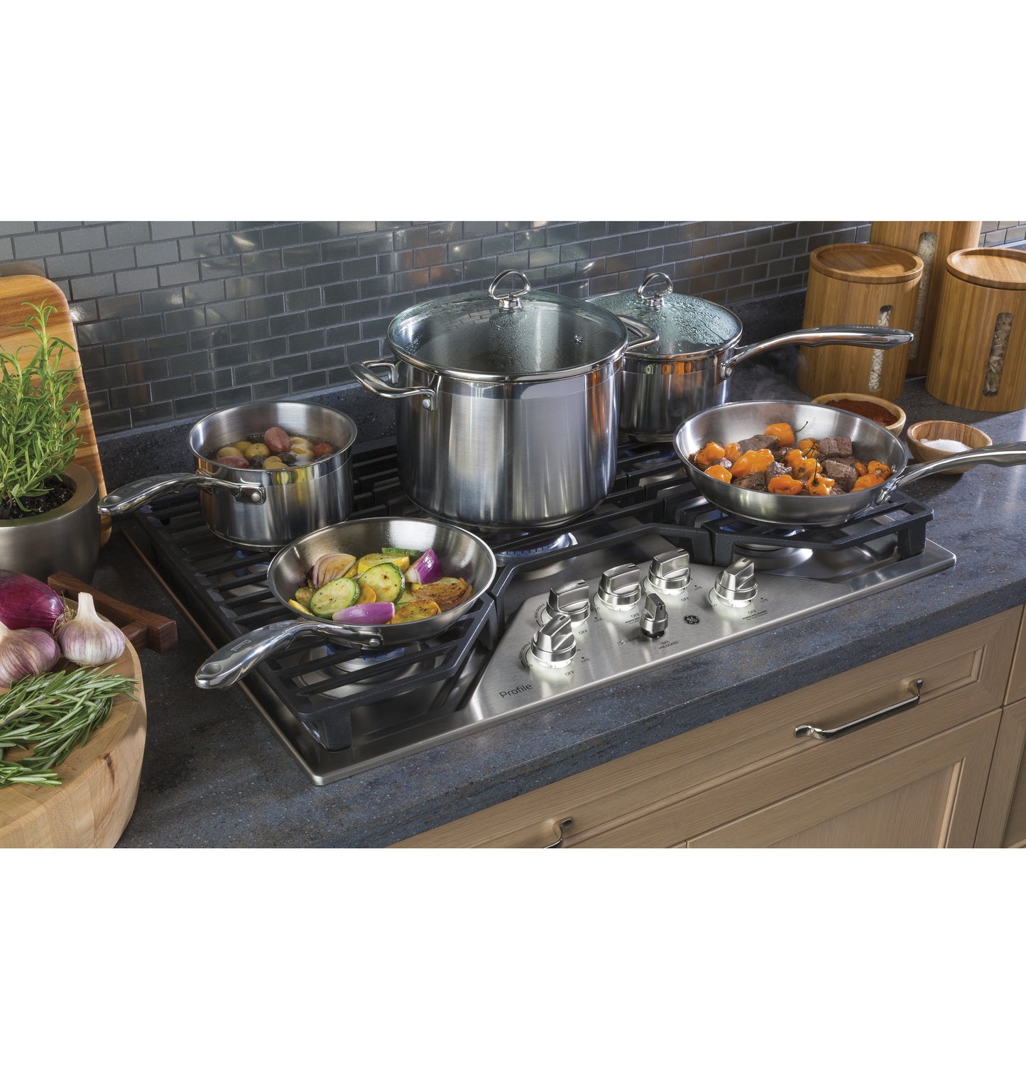 Stainless steel gas cooktop with five burners cooking vegetables and stew in a modern kitchen setting