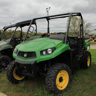 Green and yellow mid-size utility vehicle with rugged off-road tires and protective roll cage for outdoor work tasks