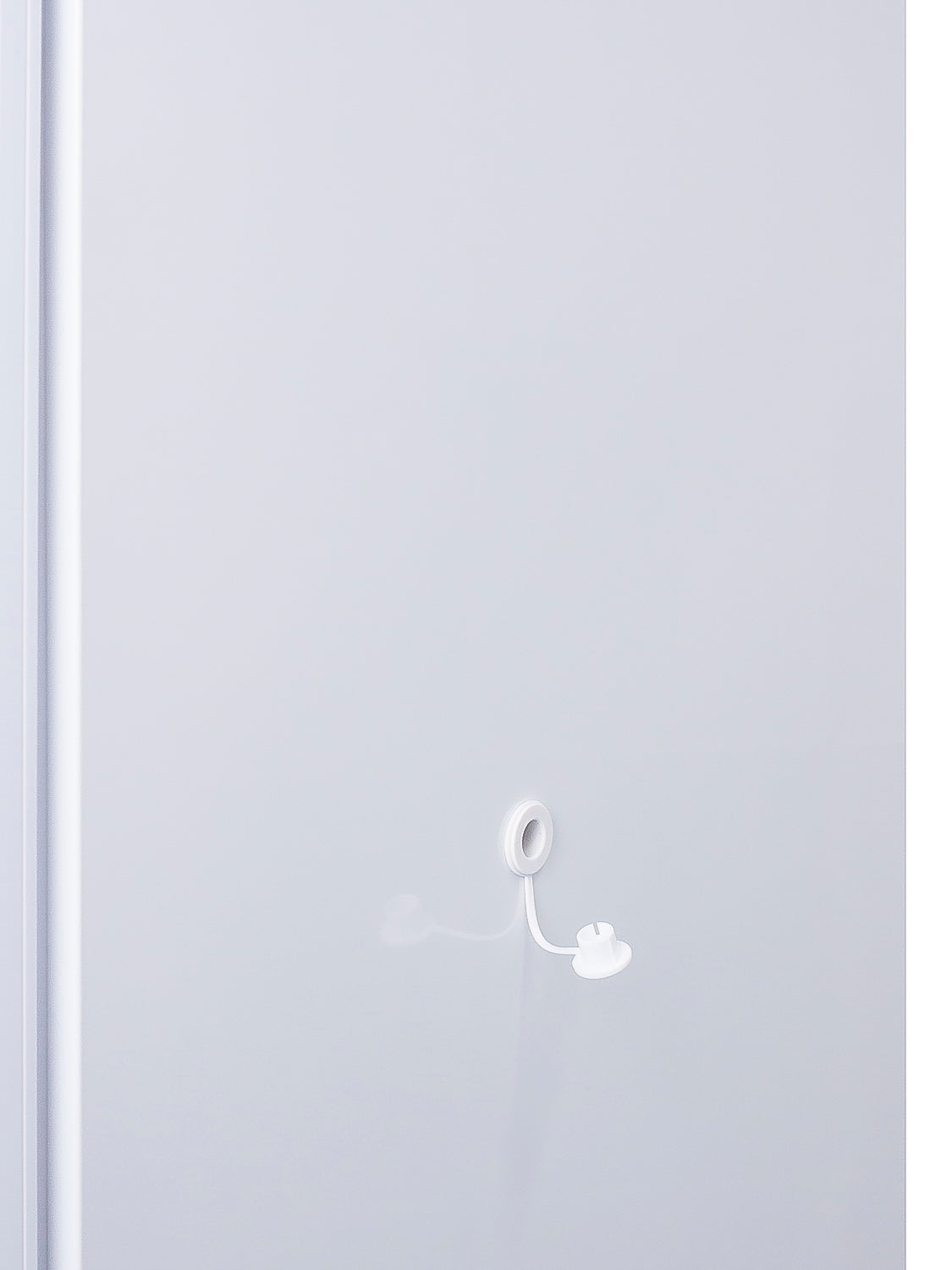 Close-up of white cable with looped end attached to plain white surface of upright freezer door in appliance setting