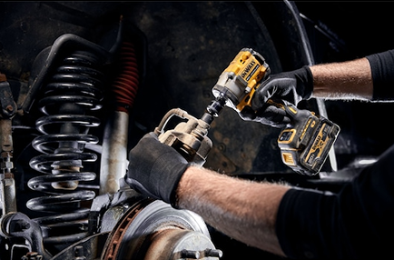 Yellow and black cordless impact wrench with hog ring being used for automotive repair on vehicle suspension components