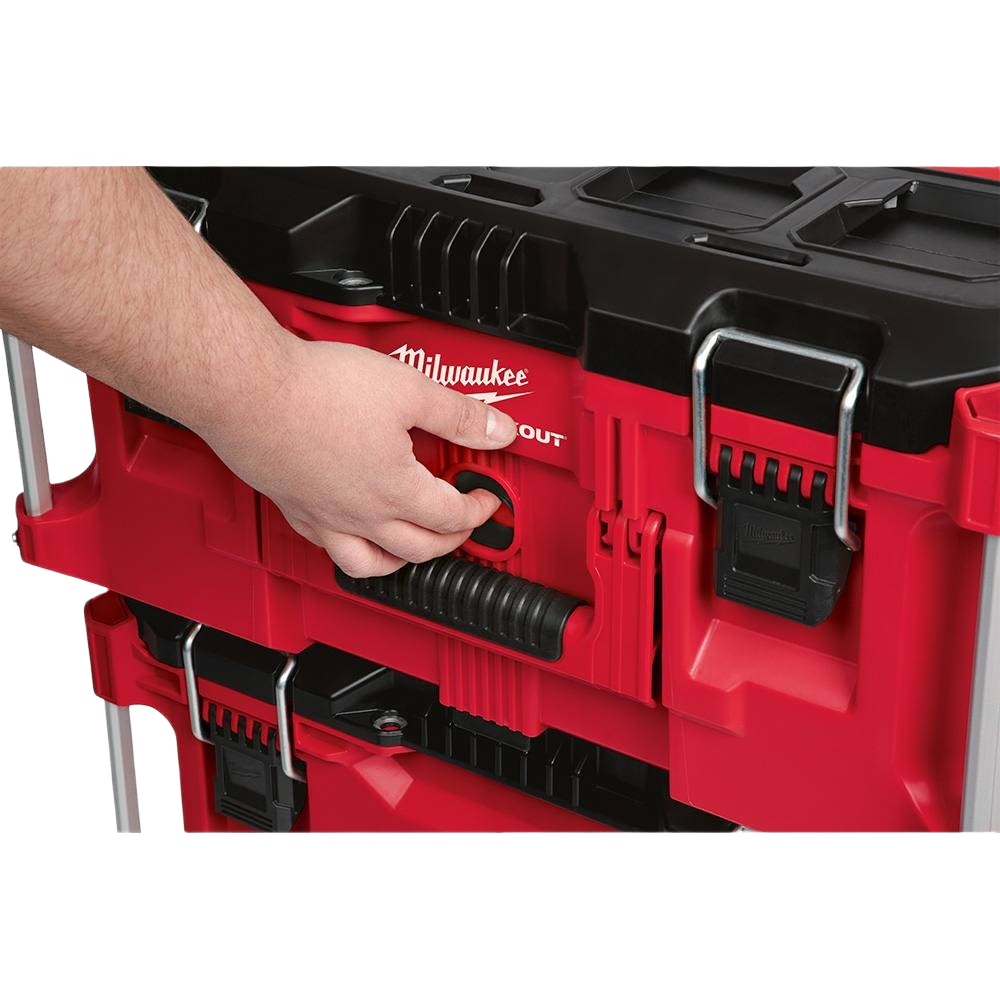 Hand securing latch on red and black Milwaukee PACKOUT™ large tool box for workshop storage and organization